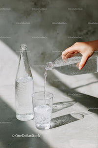 Pouring Water into a Glass with Sunlit Reflections