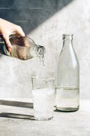 Pouring Water into a Glass with Sunlit Reflections