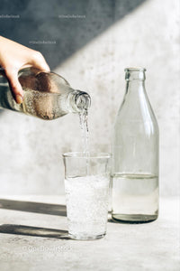 Pouring Water into a Glass with Sunlit Reflections