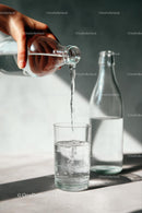 Pouring Water into a Glass with Sunlit Reflections