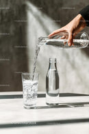 Pouring Water into a Glass with Sunlit Reflections