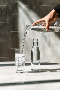 Pouring Water into a Glass with Sunlit Reflections