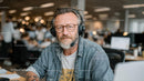 Mature Man in Headset at Modern Office Setting