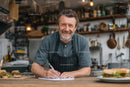 Smiling Chef in Rustic Kitchen Taking Culinary Notes