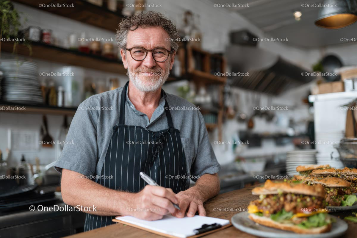 Uśmiechnięty szef kuchni pisze w kuchni restauracji