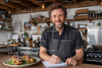 Smiling Chef Writing Notes in Rustic Kitchen