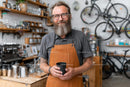 Bearded Barista Holding a Coffee Cup in a Cozy Cafe