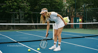 Female Tennis Player Collecting Balls on Court