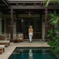 Woman Strolling in Tropical Villa with Poolside View