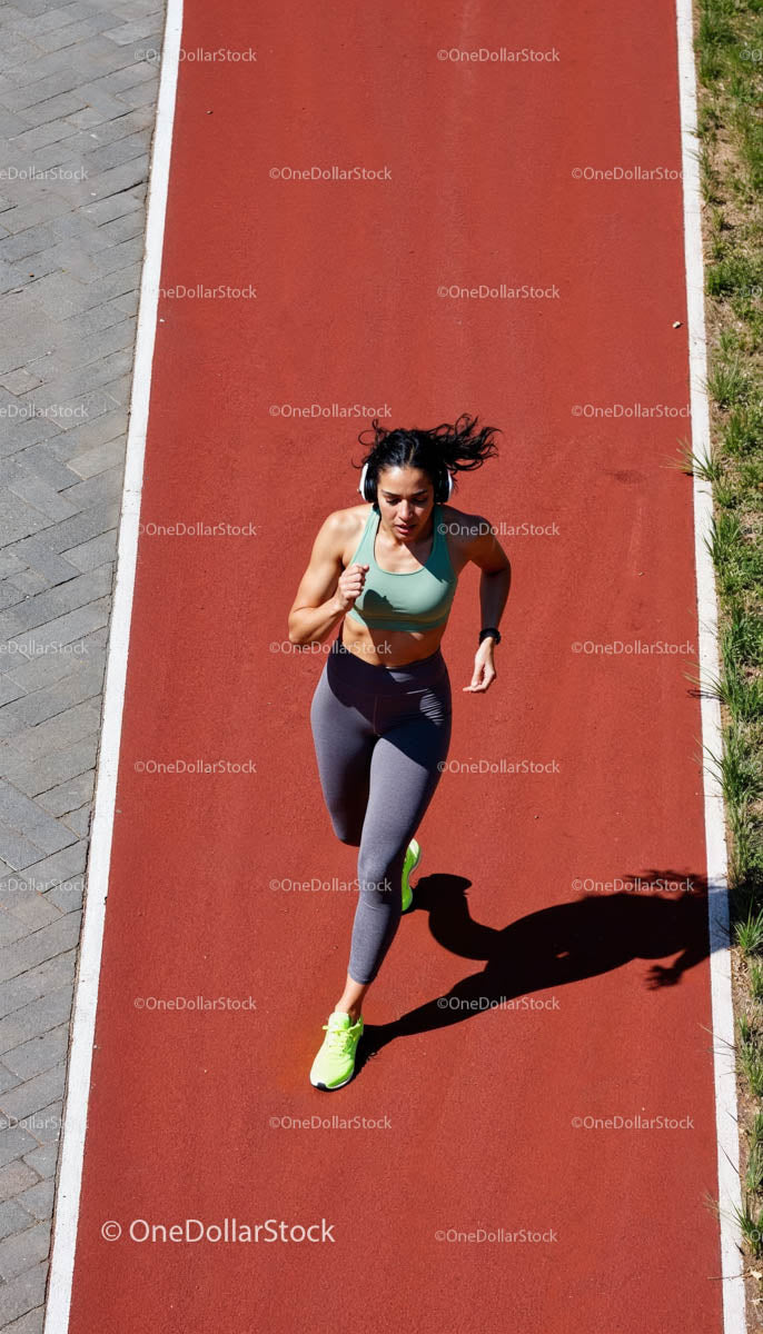 Athletic Woman Jogging on a Red Track in the Sun