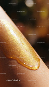 Golden shimmering body oil on smooth skin surface
