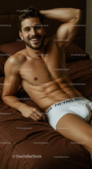 Smiling muscular man relaxing on bed in white underwear