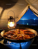 Seafood paella cooking over camp stove at night