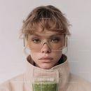 Young Woman Wearing Sunglasses Enjoying Green Smoothie in Modern Setting