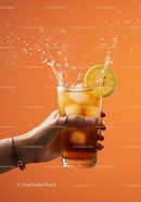 Refreshing iced tea splash with lemon slice on orange background