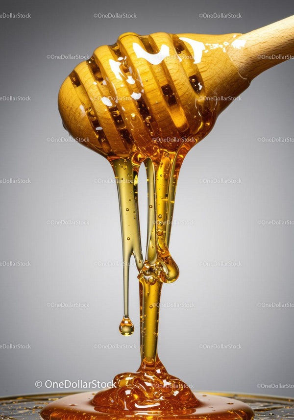 Golden honey dripping from wooden honey dipper