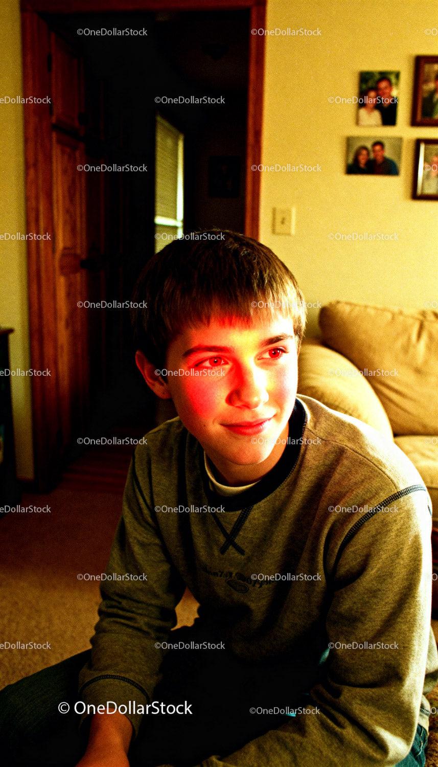 Teenage boy sitting indoors with warm light on face