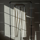 Minimalist cream trousers hanging in soft sunlight