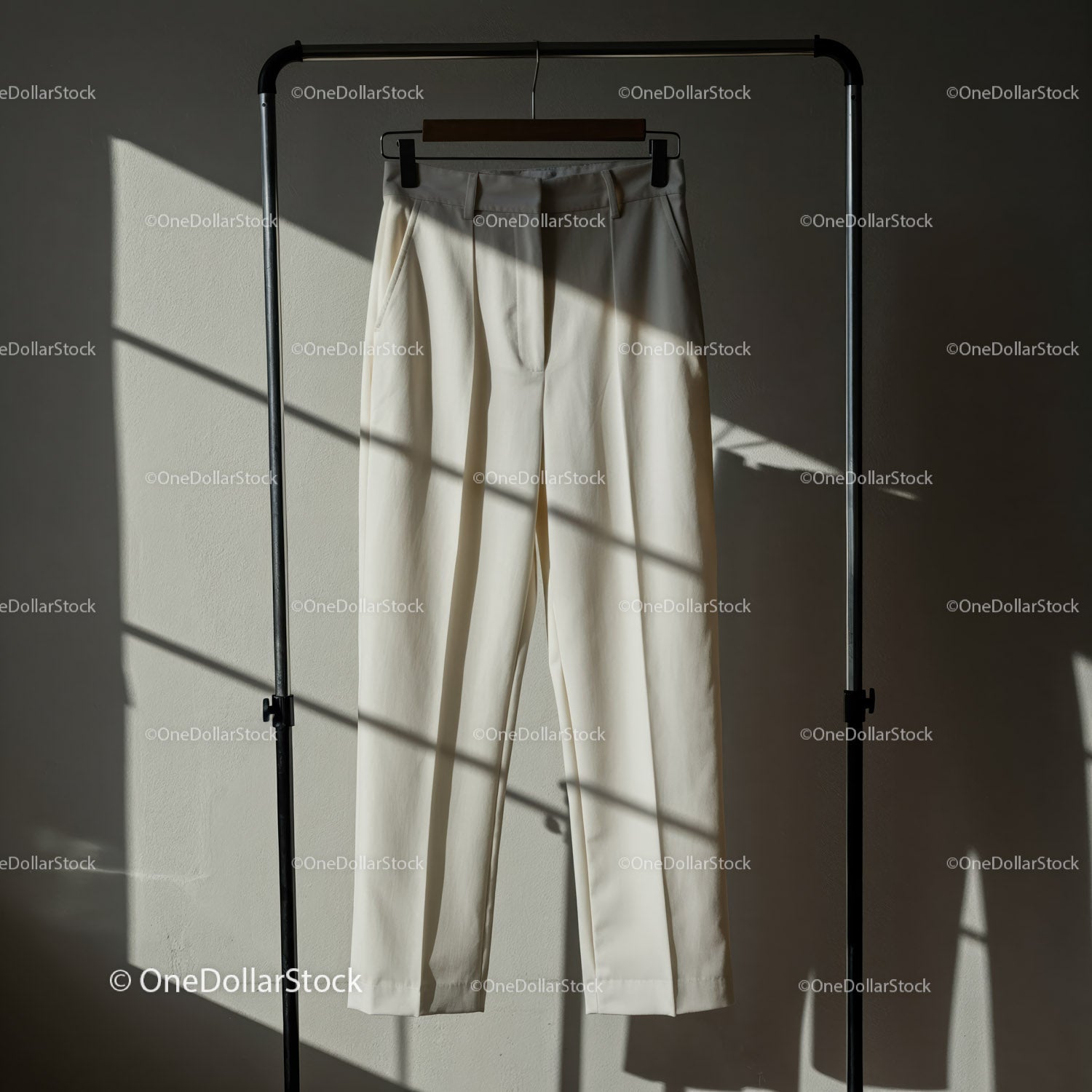 Minimalistyczne kremowe spodnie wiszące w delikatnym świetle słonecznym