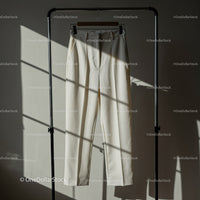 Minimalist cream trousers hanging in soft sunlight