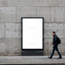 Man walking past blank urban advertising board on concrete wall