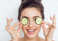 Joyful Woman Holding Cucumber Slices Over Eyes in Bright Studio