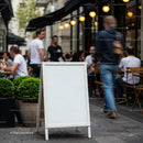 Blank street sign by bustling outdoor cafe in city