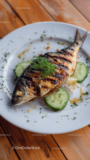 Grilled Fish with Cucumber Slices and Fresh Herbs on White Plate