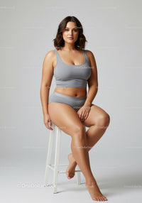 Confident Plus Size Woman Sitting on Stool Wearing Casual Gray Outfit