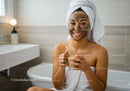 Young Woman with Facial Mask and Towel in Bathroom Relaxing