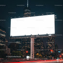 Large illuminated blank billboard over city street at night