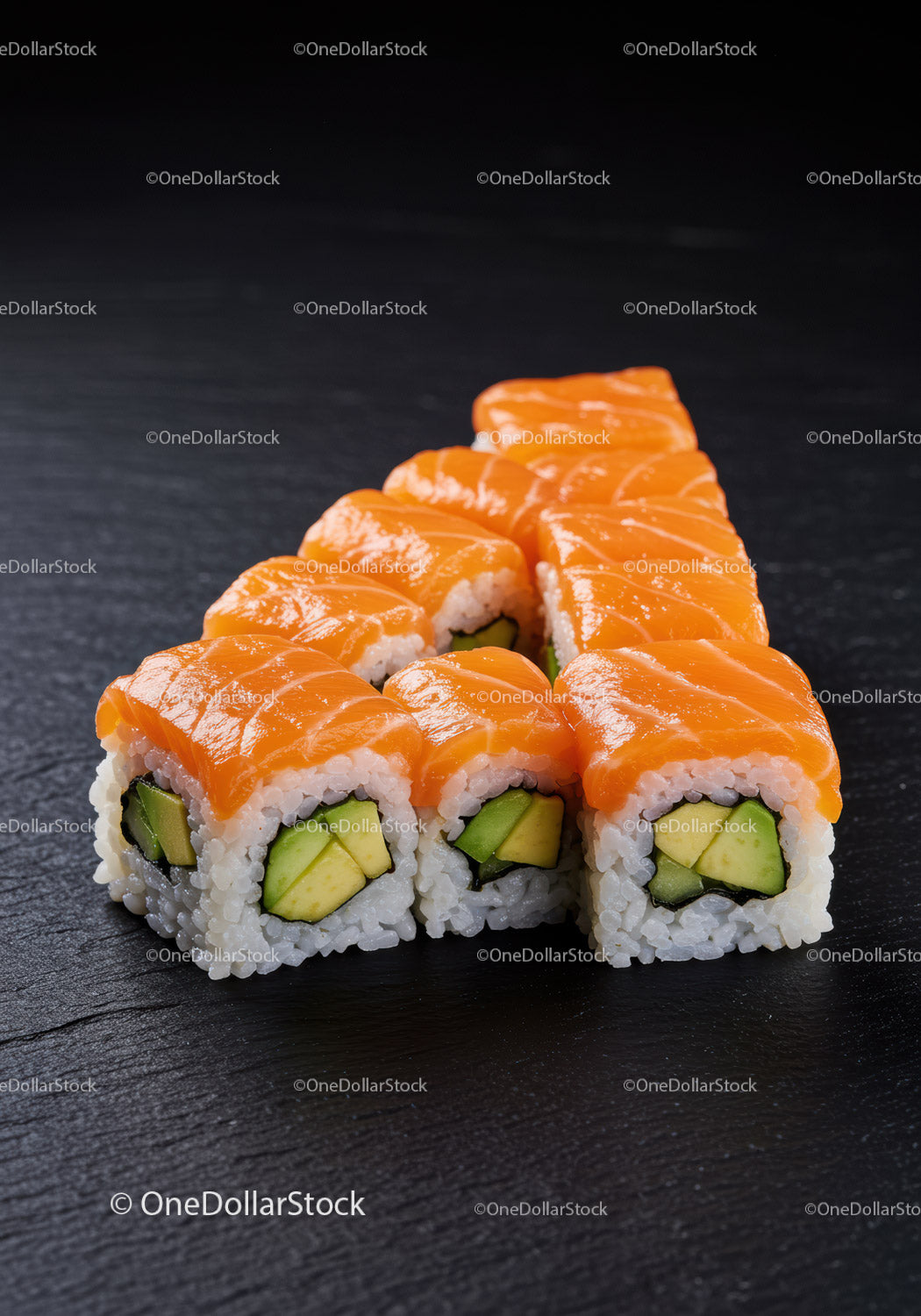 Fresh salmon sushi rolls with avocado on black slate