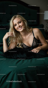 Smiling woman in black lace lingerie relaxing on bed