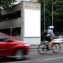 Urban street scene with cyclist and moving cars near billboard