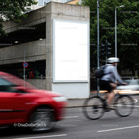 Urban street scene with cyclist and moving cars near billboard