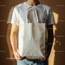 Man Holding Blank Canvas Tote Bag Against Brown Wall