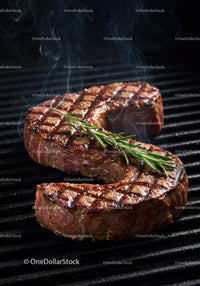 Juicy grilled steak with fresh rosemary on barbecue grill