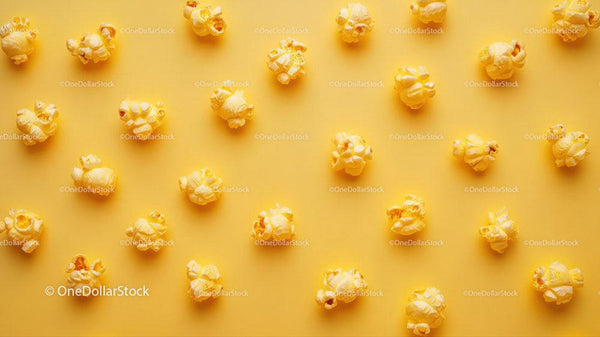 Żółty popcorn rozsypany na żółtym tle – przekąska i motyw filmowy