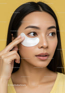 Young Woman in Yellow Applying Eye Patches for Skincare
