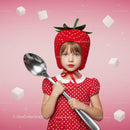 Little girl in strawberry hat holding giant spoon