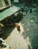 Stylish Woman Standing on Urban Sidewalk with City Vehicles and Bicycles