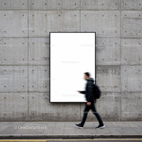Blurred man walking past blank urban poster on concrete wall
