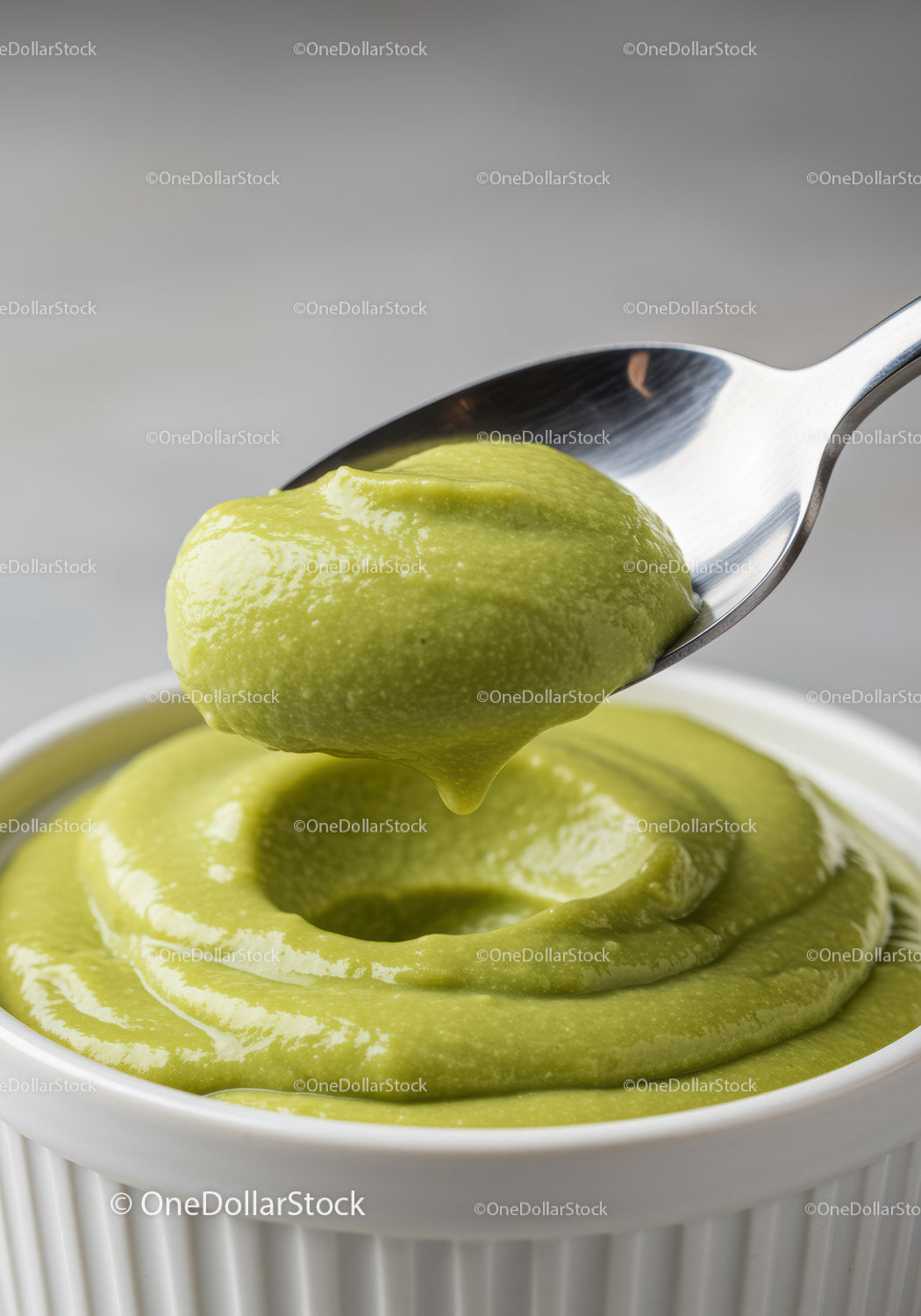 Creamy avocado sauce in white ceramic bowl with spoon