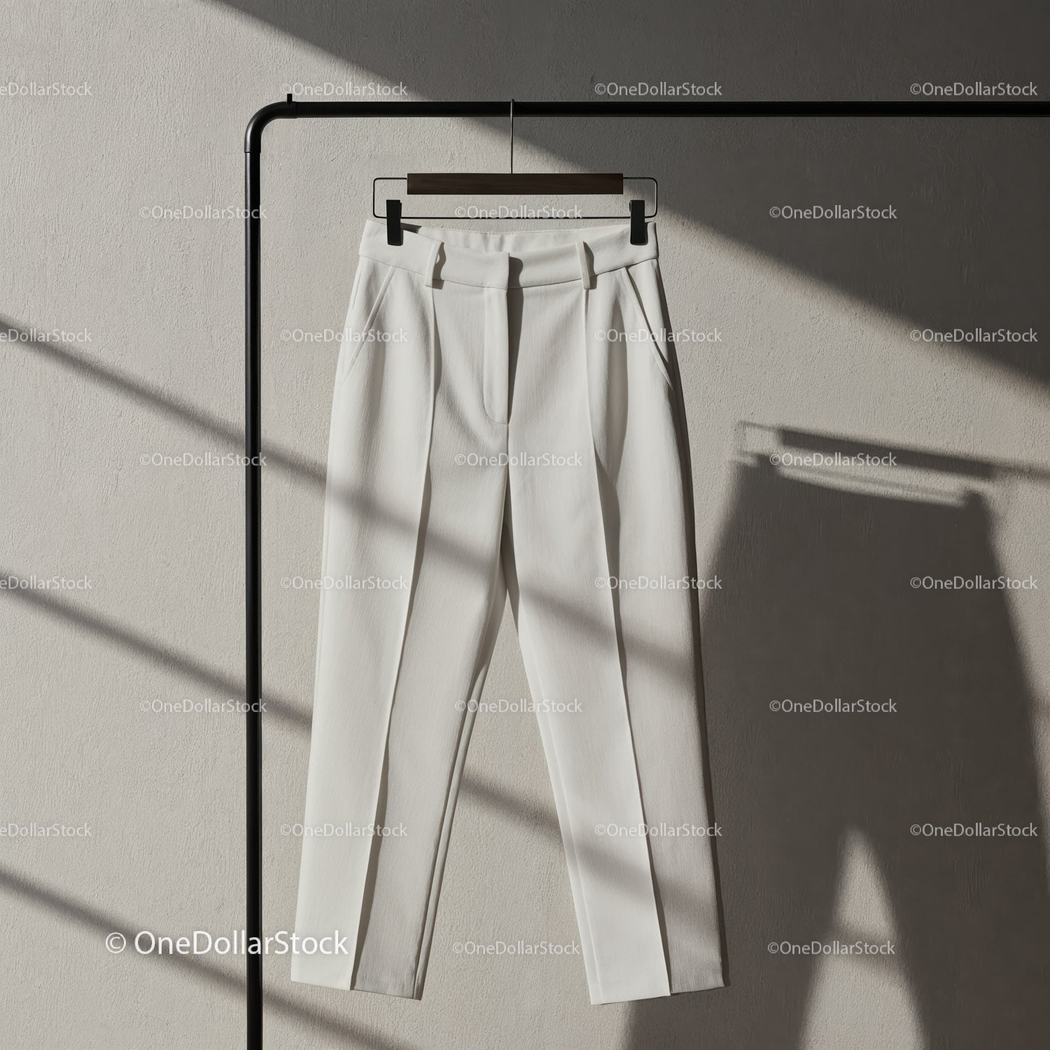 Minimalist white tailored trousers hanging on rack