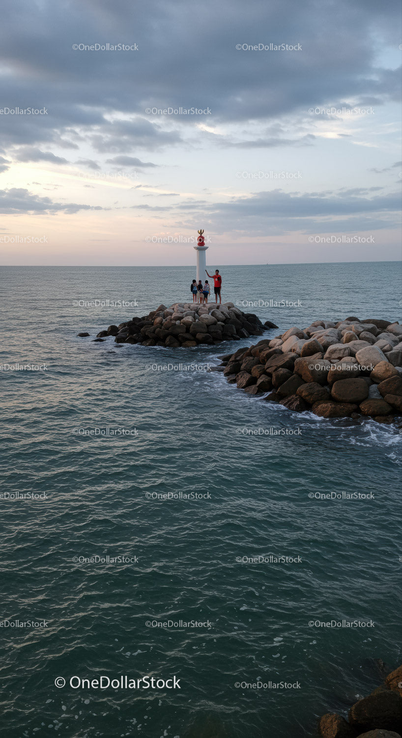 Dzieci i rodzina na zdjęciu na Rocky Shore z latarnią morską o zachodzie słońca