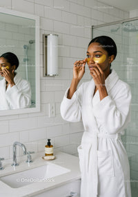 Young Woman Applying Eye Patches in Modern Bathroom For Skincare