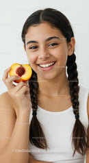 Smiling Girl in Braids Holding Peach with Pit in Bright Studio