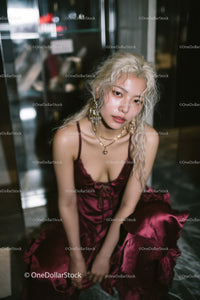 Elegant Woman in Burgundy Satin Dress with Jewelry in Modern Setting