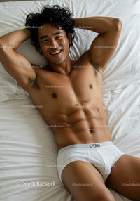 Smiling young man relaxing on bed in white underwear