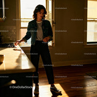 Young woman in denim jacket standing in warm kitchen light